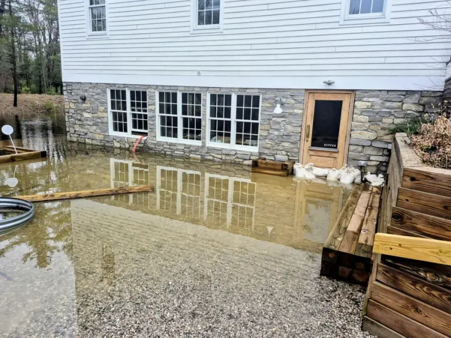 Storm water pooled against a walkout basement wall with sandbags at the door